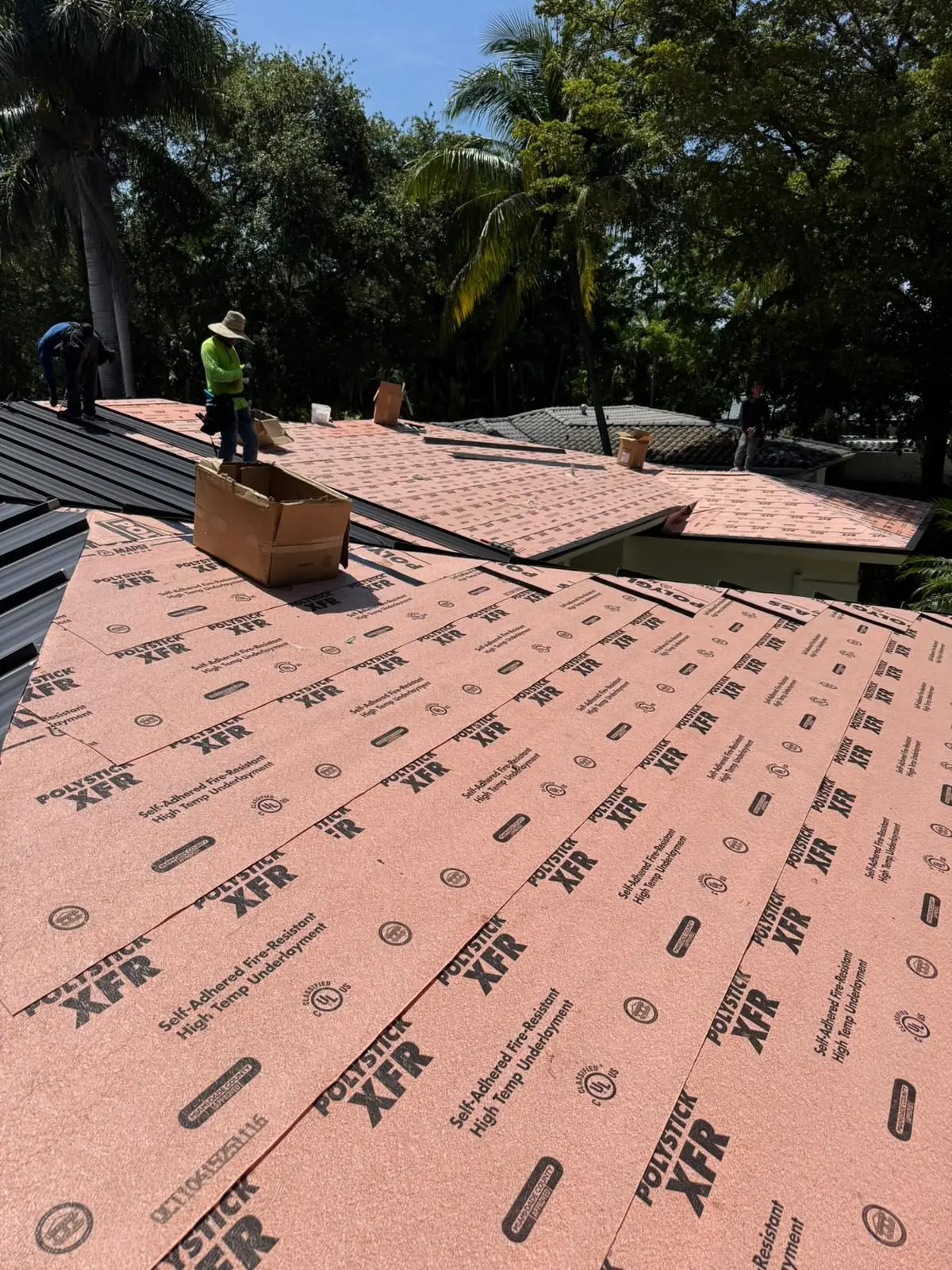 Crew installing Polystick XFR underlayment on a metal re-roof